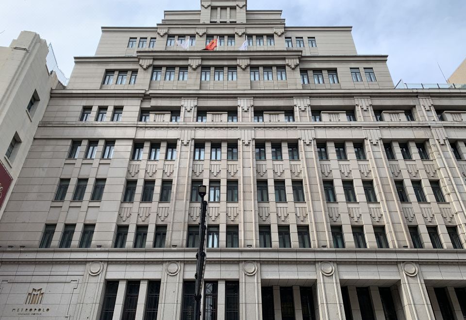 The front facade and windows of a large, old building in an urban setting are prominent features at Shanghai Jinjiang Metropolo Classic East Nanjing Road Hotel