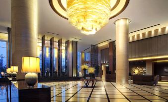 The hotel lobby features a large chandelier and glass partitions that create a stylish and elegant atmosphere at Grand Square Hotel Wuhu