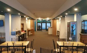 a restaurant with wooden tables and chairs , a counter , and a window overlooking the ocean at Lufra Hotel and Apartments