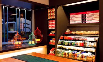a store with a variety of products on display , including beverages and snacks , next to a window at Aloft Richardson