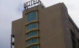 a tall building with a hotel sign on top , located in a city setting under a cloudy sky at Palm Seremban Hotel