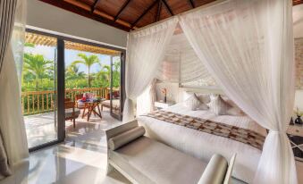 a luxurious bedroom with a canopy bed and an open door leading to a patio , overlooking a lush green garden at Salinda Resort Phu Quoc - Sparkling Wine Breakfast