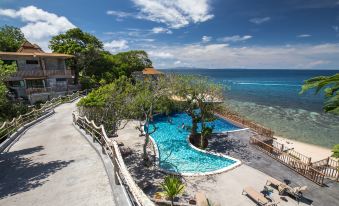 a resort with a large pool surrounded by trees and a beach in the background at Sai Daeng Resort