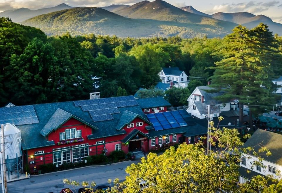 a small town with a red building and a mountain in the background , surrounded by greenery at Woodstock Inn, Station and Brewery