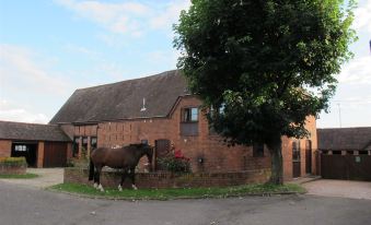 a large brick house with a horse statue in front of it , surrounded by trees at Bluebell Farm