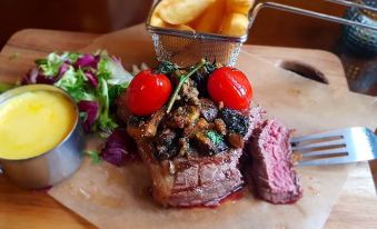a dining table with a steak on a plate , accompanied by a salad and french fries at Derby Inn