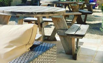 a wooden picnic table with a bench in the background , surrounded by a patio area at King William Inn