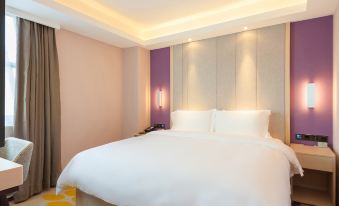 The bedroom features a spacious bed with a white and brown color scheme, accompanied by an oversized bedside table and a floor-to-ceiling window that provides a breathtaking view of the city skyline at Lavande Hotel (Beijing Changyang Metro Station)