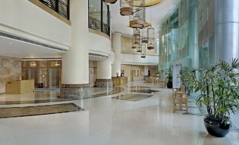 The hotel features a spacious lobby with tables and chairs in the center, as well as access to other rooms at Harbour Plaza Resort City