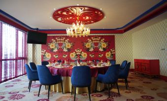 a dining room with a round table surrounded by blue chairs and a red wall at Ximei Lucky Hotel