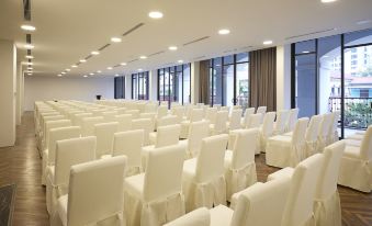 a large conference room filled with rows of white chairs and rows of windows that allow natural light to fill the space at Senna Hue Hotel