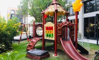 a colorful playground with various play equipment , including swings , slides , and a climbing structure , set in a grassy area near a building at Divalux Resort and Spa Bangkok, Suvarnabhumi Airport-Free Shuttle