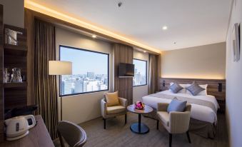 a modern hotel room with two beds , a chair , and a table , all situated near a window with a view of the city at Kawasaki Nikko Hotel