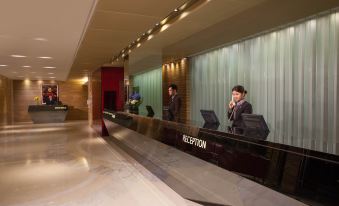 A man is seated at the front desk in an office, with other people standing behind him at Park Hotel Hong Kong