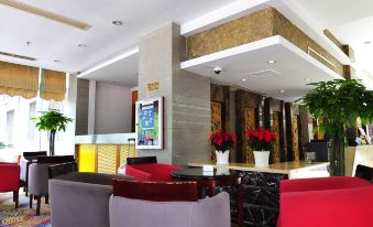 a modern hotel lobby with red and blue chairs , a large screen tv , and potted plants at Airport Hotel