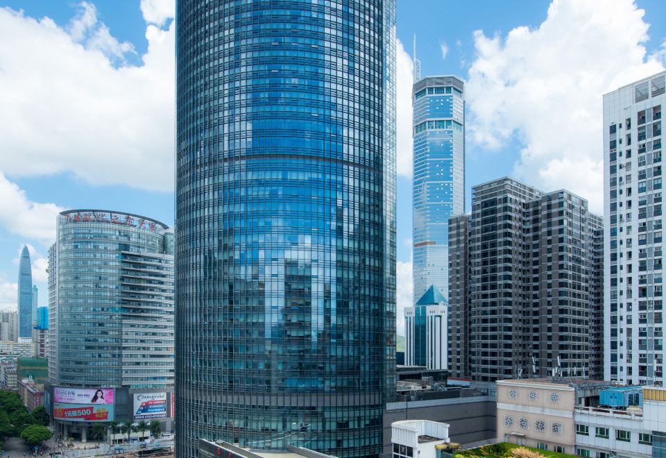 There is a large office building with multiple floors, including a tall one at the center and another on top at Shenzhen Huaqiang Plaza hotel (Huaqiangbei Metro Station)