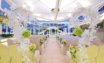 The room is decorated for a wedding with arrangements of green and white flowers on both sides at The Salisbury YMCA of Hong Kong