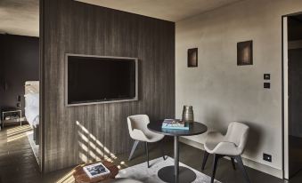 a modern living room with a flat screen tv mounted on the wall , a dining table , and two chairs at Hotel Viu Milan, a Member of Design Hotels