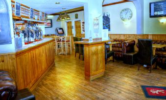 a restaurant with wooden tables and chairs , a bar counter , and a clock on the wall at Lion Hotel & Studio Apartments