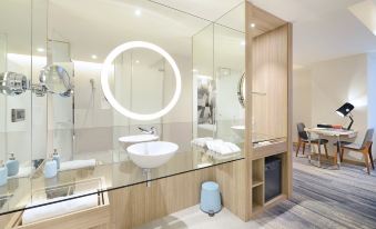 a modern bathroom with a white sink , large mirror , and wooden walls , as well as a blue trash can at Hotel Cham Cham - Taipei