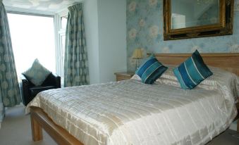 a well - decorated bedroom with a large bed , blue and white striped pillows , and a window at The Anchorage Hotel
