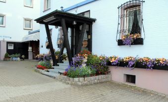 a white building with a black awning and flower pots filled with colorful flowers on the steps at Hotel Restaurant Post Italia