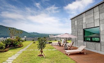 a large house with a patio area that has a wooden deck and lounge chairs at Hotel the One