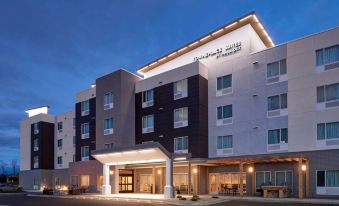 a large hotel building with a white and black facade , lit up at night at TownePlace Suites Grand Rapids Airport