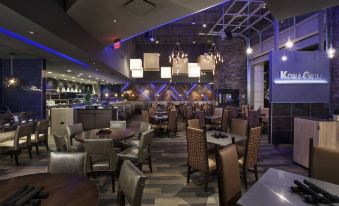 a modern restaurant interior with multiple dining tables , chairs , and a bar area under the ceiling at AC Hotel Cincinnati at Liberty Center