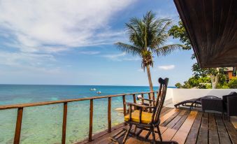 a wooden deck overlooking the ocean , with two rocking chairs placed on the deck for relaxation at Taatoh Seaview Resort