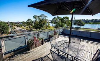 a rooftop patio with a dining table , chairs , and an umbrella providing shade for the table at Cockatoo Island Accommodation