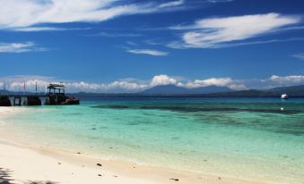 a beautiful beach scene with clear blue water , white sand , and a pier extending into the ocean at Gangga Island Resort & Spa