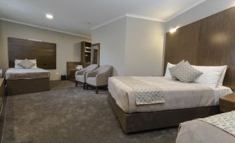 a modern hotel room with two beds , each having white bedding and pillows , accompanied by gray carpeting and wooden furniture at Bankstown Motel 10