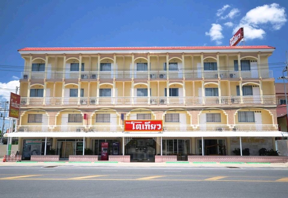 a large , yellow building with red roof tiles and balconies , situated on a city street at Tokyo Hotel