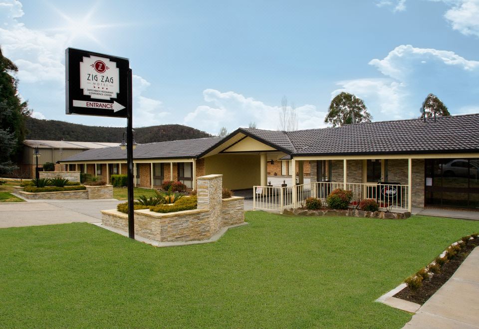 a two - story building with a red roof and white trim , situated on a grassy area at Zig ZAG Motel & Apartments