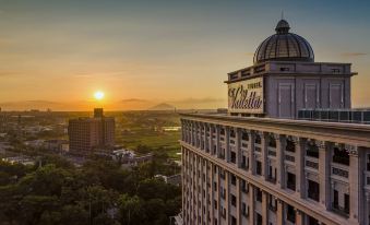 "a tall building with a dome and the name "" valbella "" on top , surrounded by trees and a city skyline at sunset" at Hotel Valletta