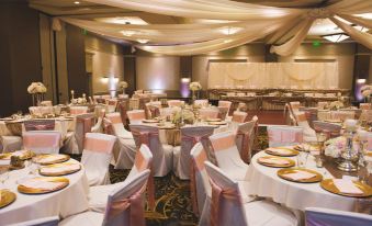 a large banquet hall with many tables and chairs , each table set with a white tablecloth and gold plates at Chautauqua Harbor Hotel - Jamestown