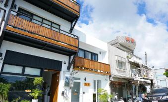 a white building with wooden balconies and a metal railing is situated on a street at Red House