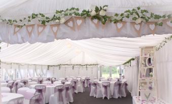 a wedding reception with multiple tables covered in white tablecloths and decorated with flowers , creating a romantic atmosphere at The Britannia Inn & Waves Restaurant
