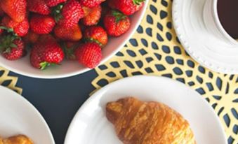 a table with a bowl of strawberries , two croissants , and a cup of coffee at The Studio