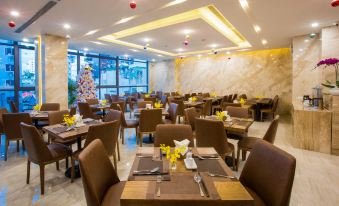 a modern restaurant with multiple dining tables , chairs , and a christmas tree in the background at DTX Hotel Nha Trang