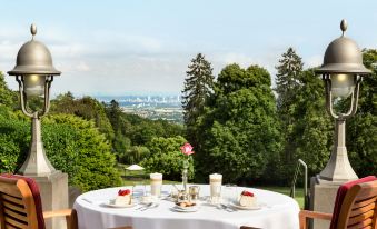 a dining table set for two people , with a view of a city in the background at Falkenstein Grand, Autograph Collection