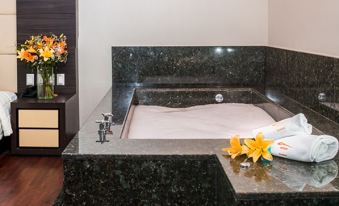 a bathroom with a large bathtub surrounded by black granite , creating a modern and elegant atmosphere at Hotel Astor