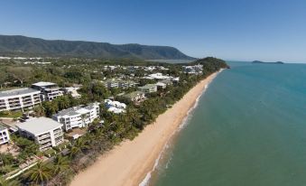 aerial view of a beach with a sandy shoreline , surrounded by buildings and trees , near a body of water at On the Beach Apartments