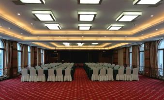 a large , empty banquet hall with rows of white chairs and red carpet under the ceiling at Rome Hotel