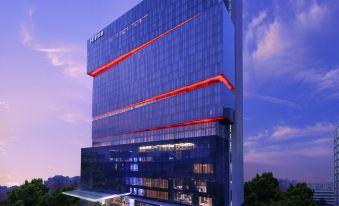 The rendering depicts the illuminated facade and glass panels of the hotel's exterior at night at Hilton Guangzhou Tianhe