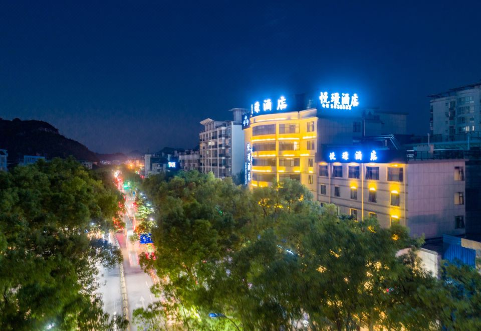 a city street at night , with a tall building in the background and numerous cars parked on the side of the road at GuiLin ParkView Hotel