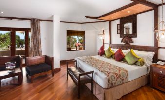 a spacious bedroom with a king - sized bed , hardwood floors , and a large window overlooking a forest at Royal Palms Beach Hotel