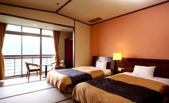 a hotel room with two beds , one on the left and one on the right side of the room at Nagasaki Nisshokan