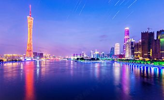 A city's illuminated skyline at night with a blue waterfront at Discovery Hotel (Guangzhou Railway Station Sanyuanli Subway Station)